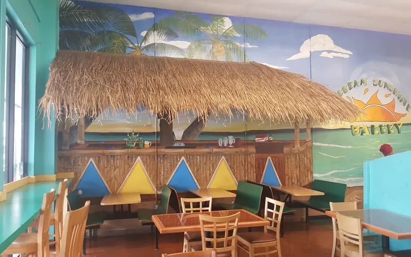 A restaurant with tables and chairs and a mural on the wall.