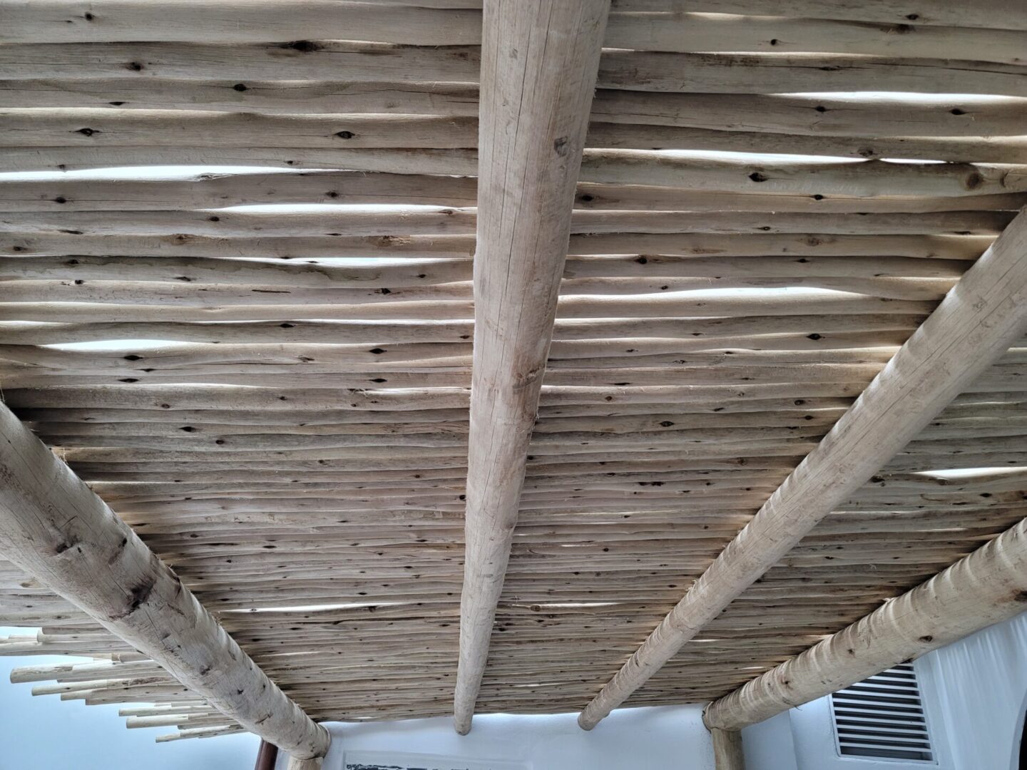 The ceiling of a room is covered with wooden beams.