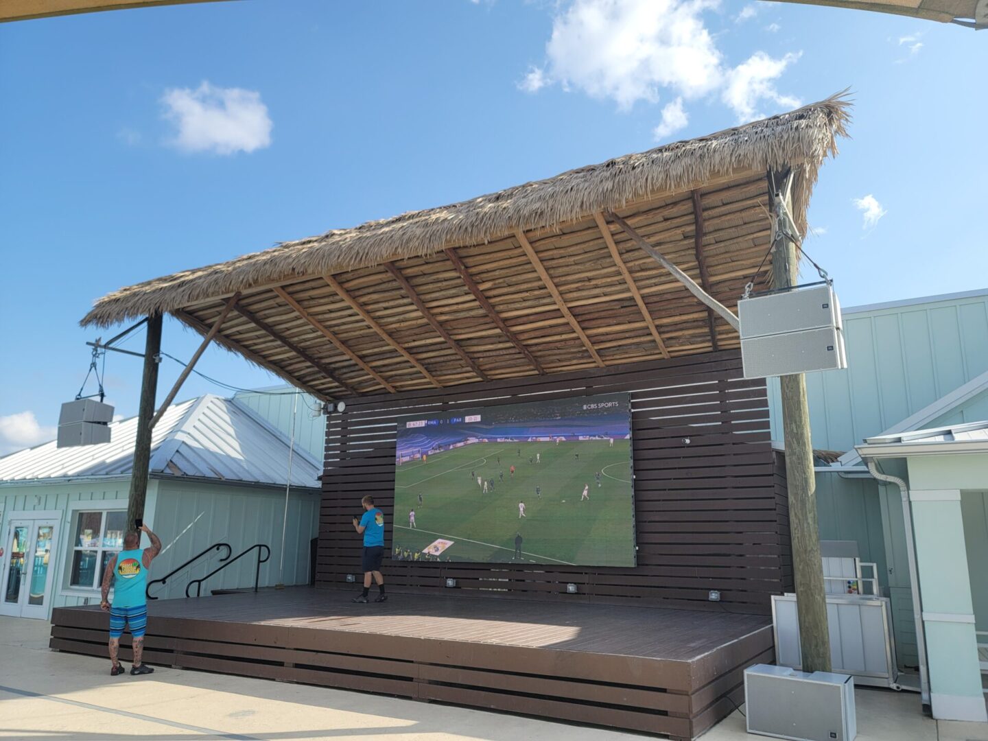 A large screen showing a soccer game on a deck.