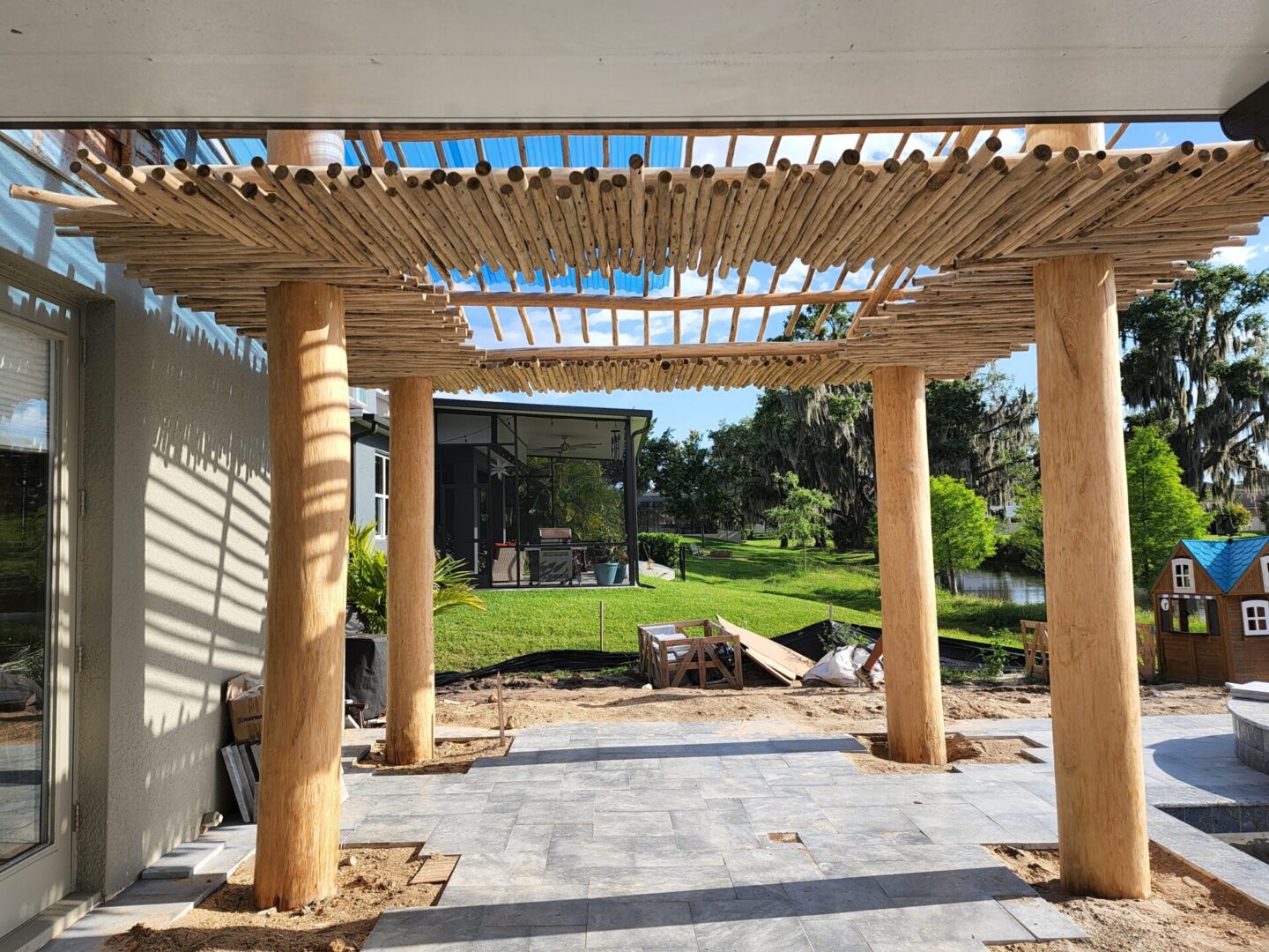A wooden pergola is being built in a backyard.