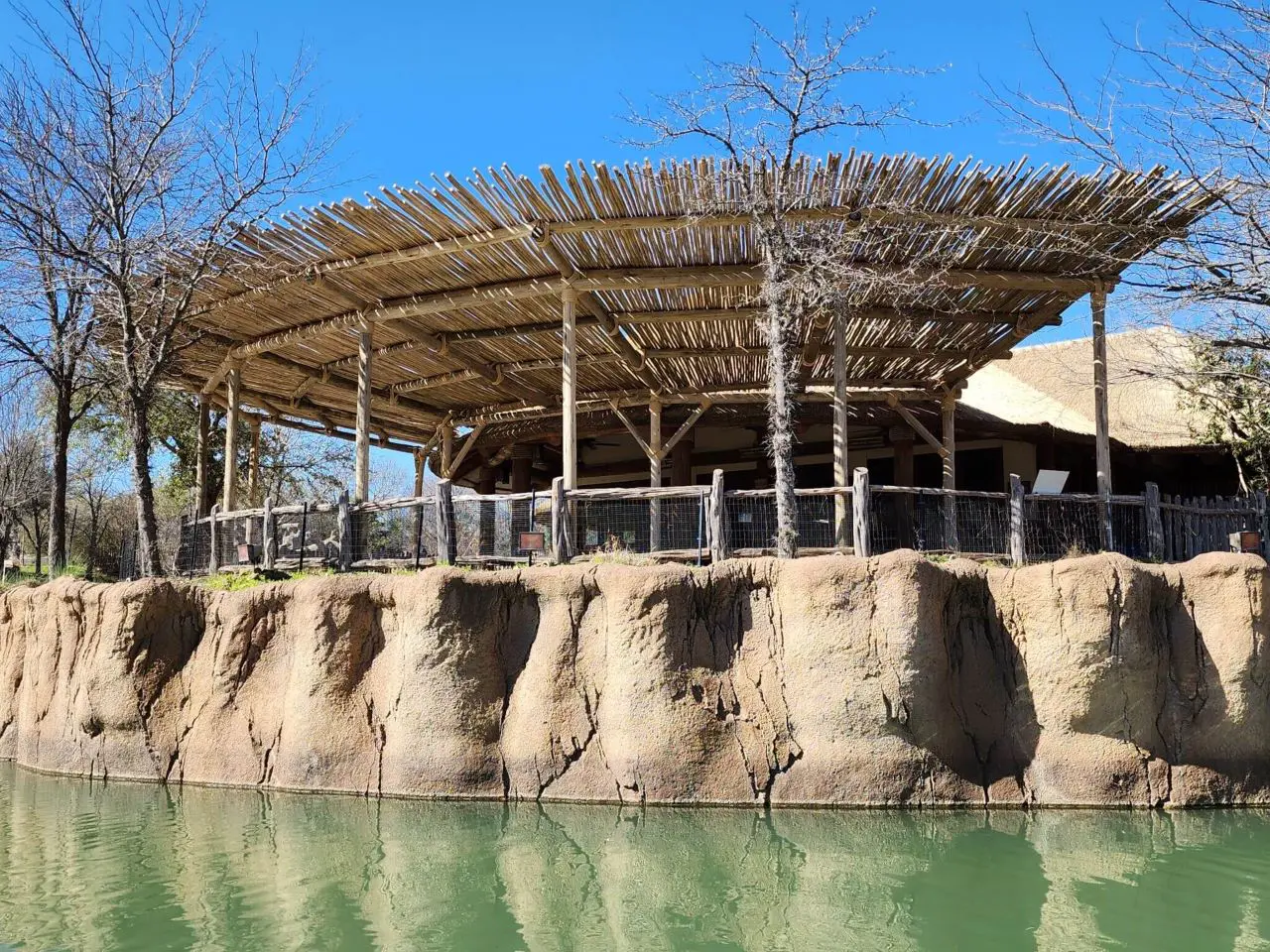 A zoo with a wooden structure and a pond.