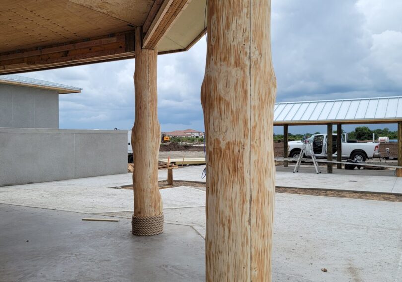 A building with wooden columns and a concrete floor.