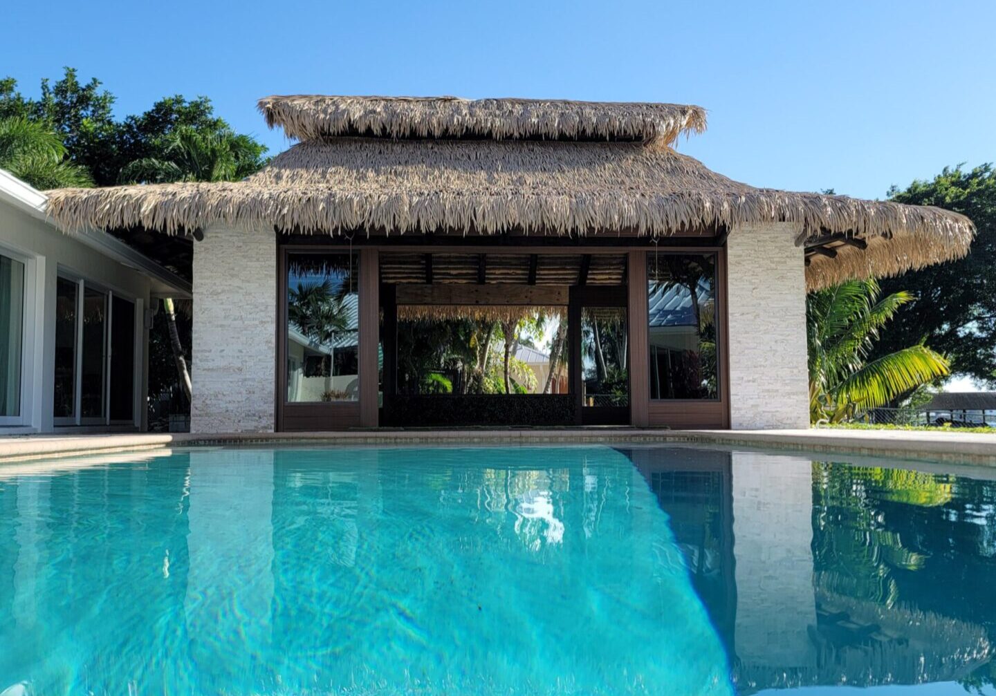 A swimming pool with a thatched roof.