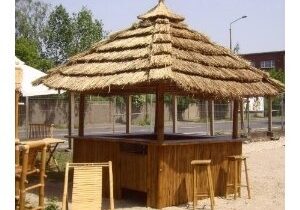 A tiki hut with chairs and a thatched roof.