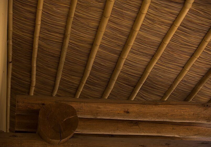 A room with a bamboo ceiling and wooden beams.